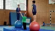 Kinder führen Zirkusnummern in einer geschmückten Schulsporthalle auf, Publikum schaut begeistert zu