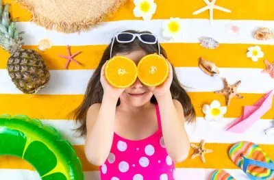 Sommerferien - Mädchen auf einem Strandtuch am Meer.