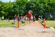 Kinder beim Weitsprung auf dem Sportplatz im Freien bei sommerlichem Wetter
