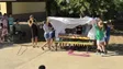 Bunt gestaltete Mitspielbank auf einem Grundschulhof, umgeben von Kindern bei der Einweihungsfeier