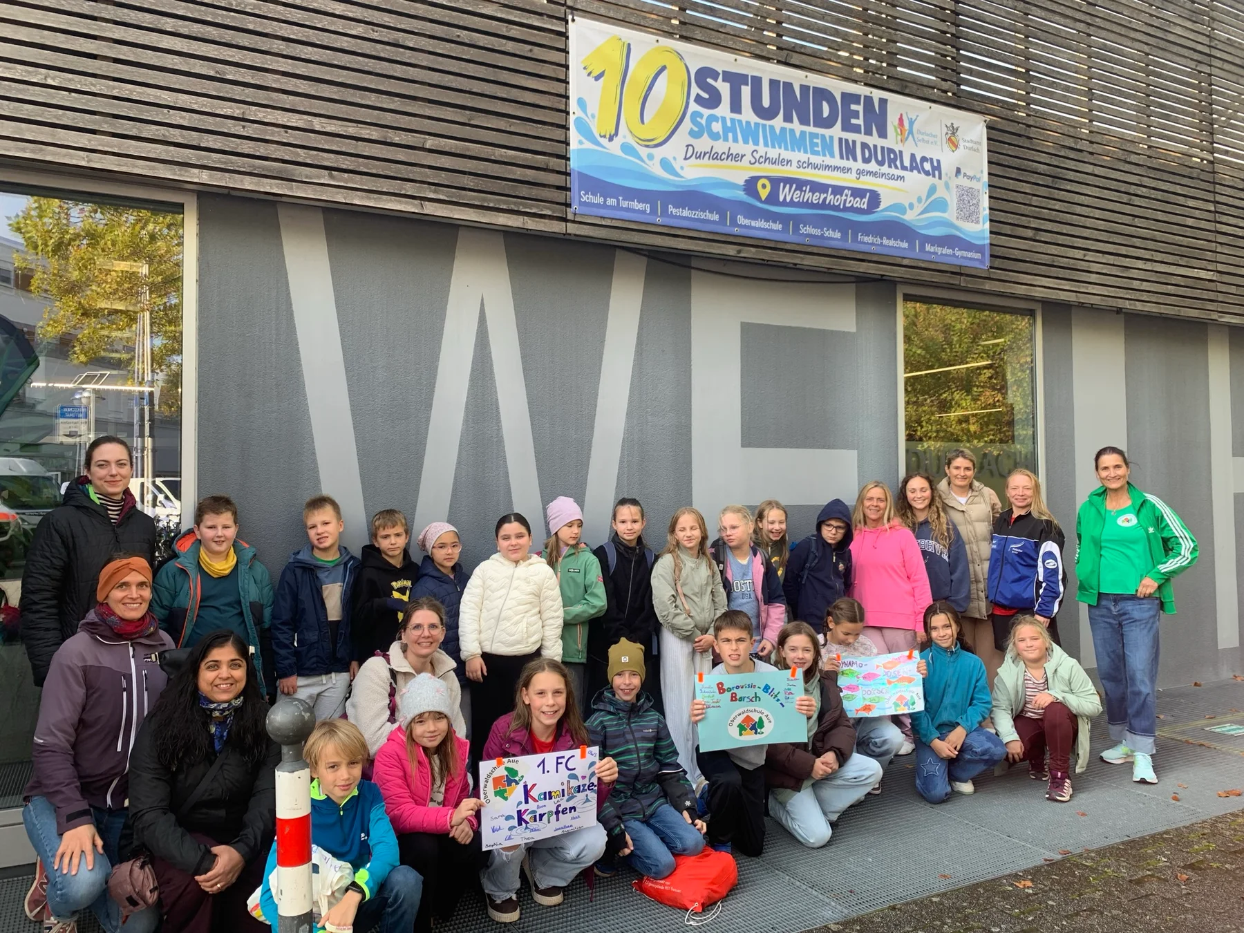 Kinder und Erwachsene der Oberwaldschule mit ihren Teamplakaten vor dem Weiherhofbad.
